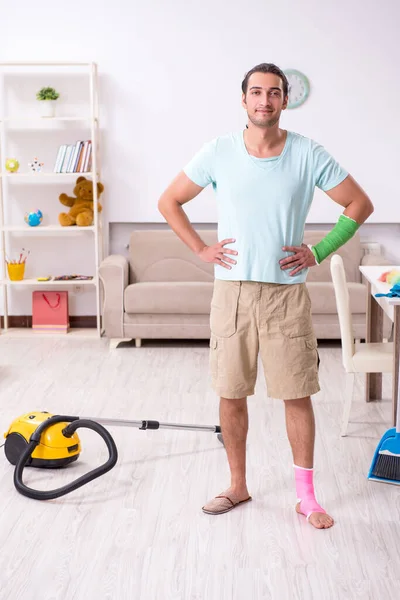 Jonge gewonde man die het huis schoonmaakt — Stockfoto