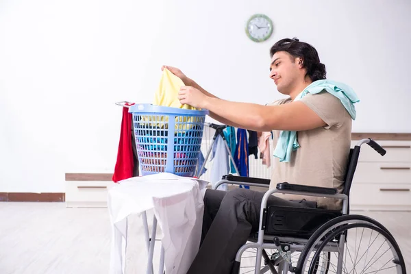 Tekerlekli sandalyedeki genç adam evde ütü yapıyor. — Stok fotoğraf