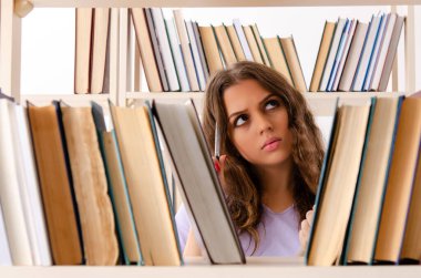 Genç kız öğrenci kütüphanede sınava hazırlanıyor.