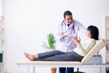 Genç doktor yaşlı yaşlı kadını muayene ediyor.