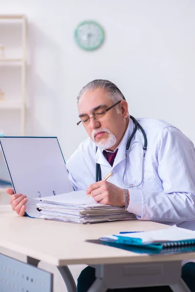 Klinikte çalışan yaşlı erkek doktor. — Stok fotoğraf