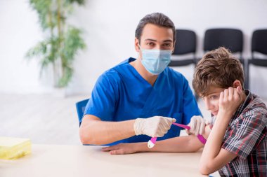 Genç çocuk hastanede doktoru ziyaret ediyor.
