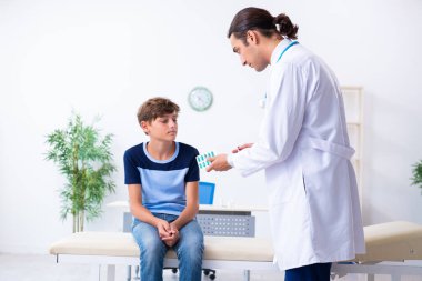 Genç erkek doktor klinikteki çocuğu muayene ediyor.