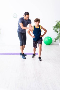 Genç baba ve oğlu egzersiz yapıyor.