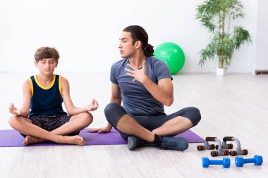 Genç baba ve oğlu egzersiz yapıyor.