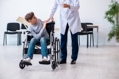 Genç erkek doktor pediatrist ve tekerlekli sandalyedeki çocuk.