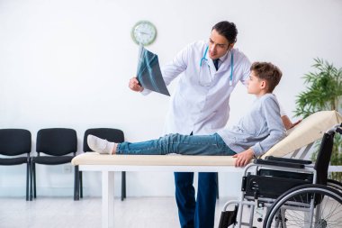 Genç erkek doktor pediatrist ve tekerlekli sandalyedeki çocuk.
