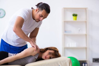 Genç bir kadın erkek doktor fizyoterapisti ziyaret ediyor.