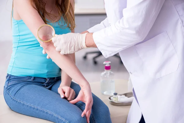 Jovem braço ferido mulher visitando jovem médico traumatologista — Fotografia de Stock