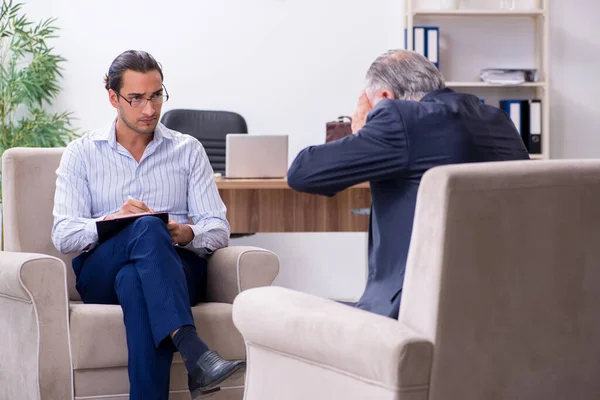 Oude man op bezoek bij jonge mannelijke dokter psycholoog — Stockfoto