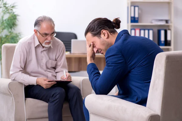 Young man visiting old male doctor psychologist — Stock Photo, Image