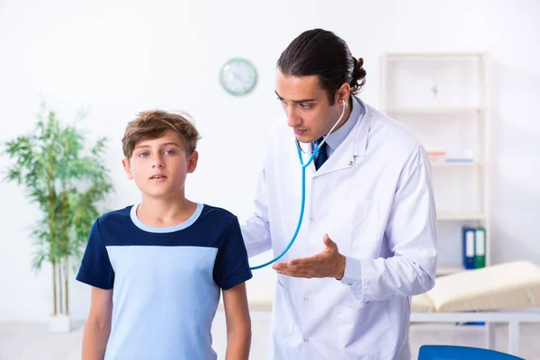 Νεαρός άνδρας γιατρός που εξετάζει το αγόρι στην κλινική — Φωτογραφία Αρχείου
