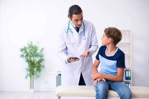 Jovem médico examinando menino na clínica — Fotografia de Stock