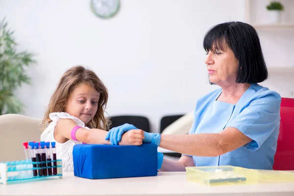 Menina visitando velho médico feminino — Fotografia de Stock