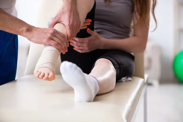 Zraněná noha žena na návštěvě mladý lékař traumatolog — Stock fotografie
