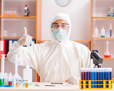 Laboratuvarda çalışan koruyucu elbise giyen genç bir biyokimyacı.