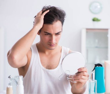 Genç yakışıklı adam aynaya bakıyor.