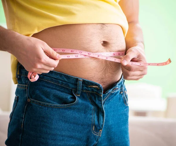 Homem que mede gordura corporal com fita métrica no conceito de dieta — Fotografia de Stock