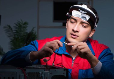 Bilgisayar uzmanı gece geç saatlerde bilgisayarı tamir ediyor.