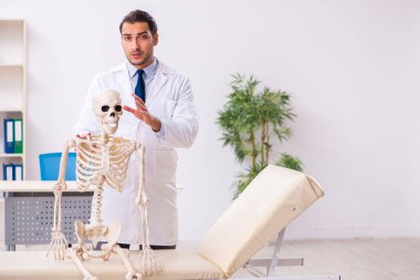 İskeleti olan genç erkek doktor.