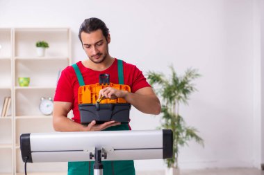 Genç erkek müteahhit içeride ısıtıcıyı tamir ediyor.