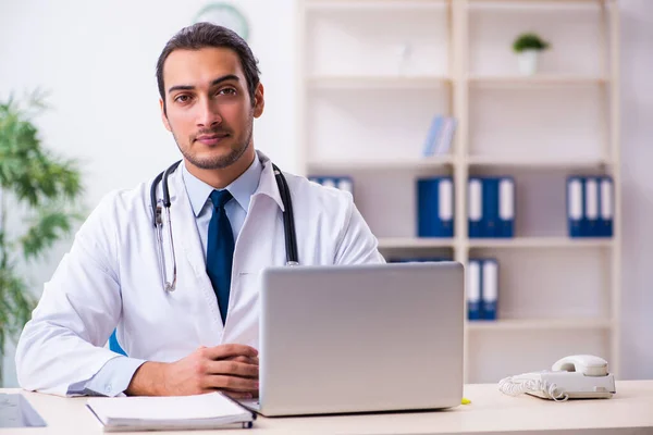 Joven hombre guapo médico que trabaja en la clínica —  Fotos de Stock