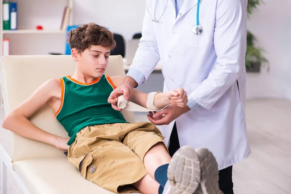 Zieke jongen op bezoek bij jonge mannelijke arts kinderarts — Stockfoto