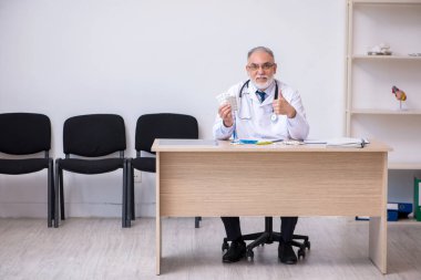 Klinikte çalışan yaşlı erkek doktor.