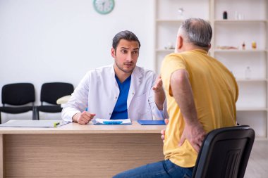 Yaşlı hasta genç erkek doktoru ziyaret ediyor.