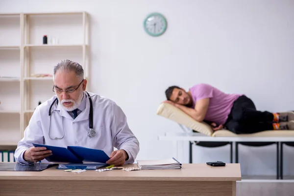 Ung manlig patient besöker gamla manliga läkare — Stockfoto