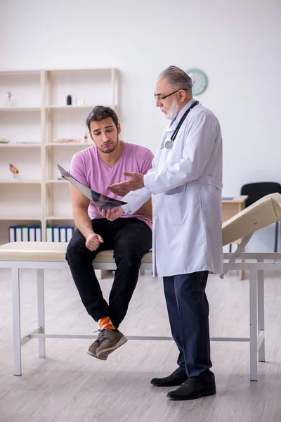 Vecchio medico radiologo esaminando giovane paziente maschile — Foto Stock