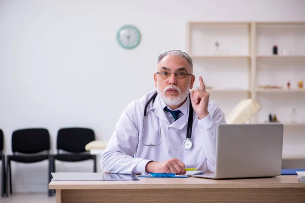 Gammal manlig läkare som arbetar på kliniken — Stockfoto