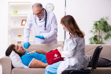 İki doktor hasta bir genci ziyaret ediyor.