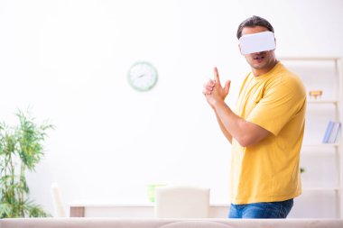Evde sanal gerçeklik gözlüklü genç bir adam