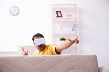 Evde sanal gerçeklik gözlüklü genç bir adam