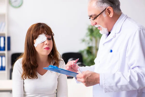 Mujer joven visitando al viejo doctor oftalmólogo —  Fotos de Stock