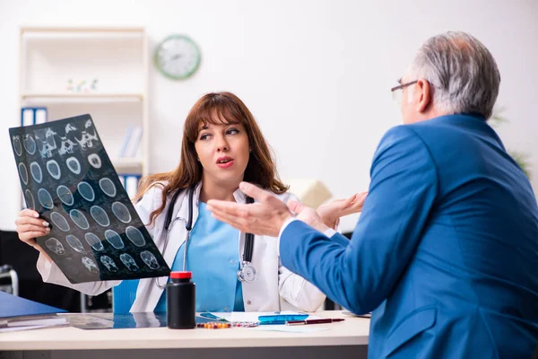 Gammal affärsman besöker ung kvinnlig läkare — Stockfoto