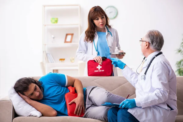 Zwei Ärzte besuchen kranken jungen Mann zu Hause — Stockfoto