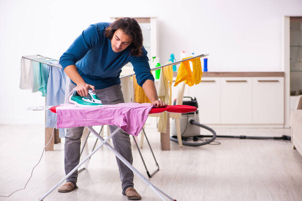 Молодой человек муж гладит одежду дома
