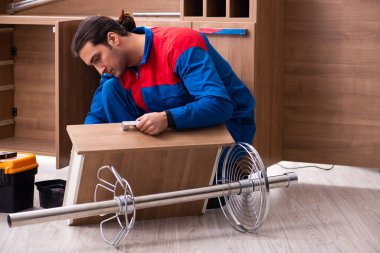 Genç yakışıklı erkek marangoz içeride çalışıyor.