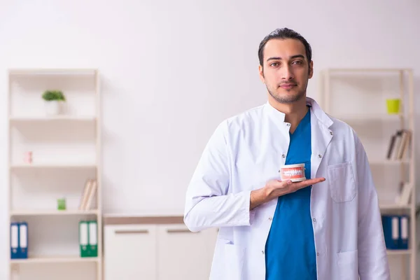 Jonge mannelijke tandarts werkzaam in de kliniek — Stockfoto