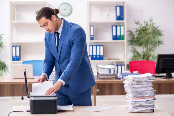Young male employee making copies at copying machine — Stock Photo, Image