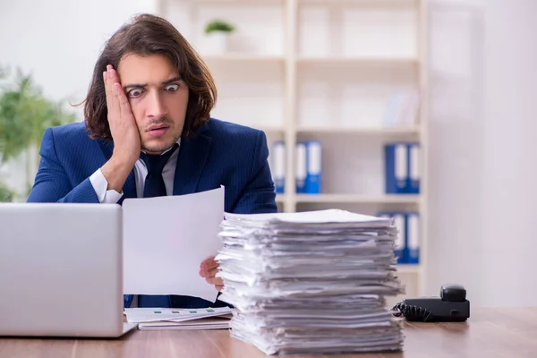 Joven empleado masculino infeliz con el trabajo excesivo — Foto de Stock