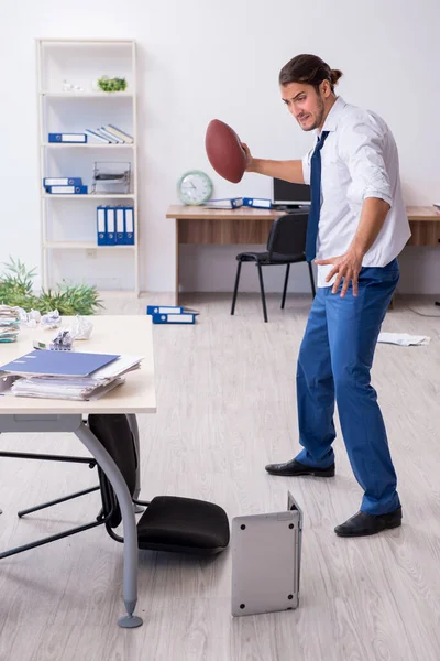 Young male employee throwing rugby ball in the office