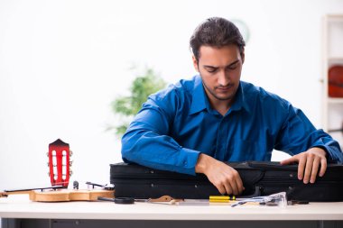 Kemanı tamir eden genç bir erkek tamirci