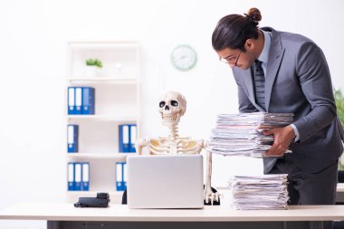 Genç erkek çalışan ve iskelet ofiste.