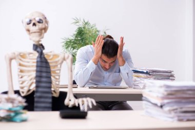 Genç erkek çalışan ve iskelet ofiste.