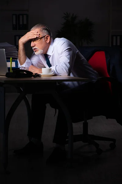 Velho empregado do sexo masculino que trabalha até tarde no local de trabalho — Fotografia de Stock