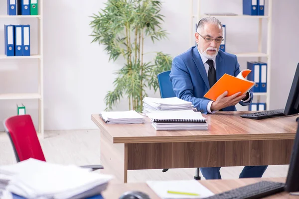 Gammal manlig anställd och överdrivet arbete på kontoret — Stockfoto