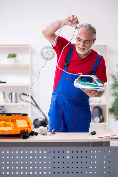 Ancien entrepreneur masculin réparer le fer à l'intérieur — Photo